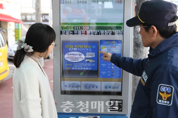 경찰관이 시민에게 승강장 버스정보기를 이용해 탄력순찰을 홍보하고 있다.