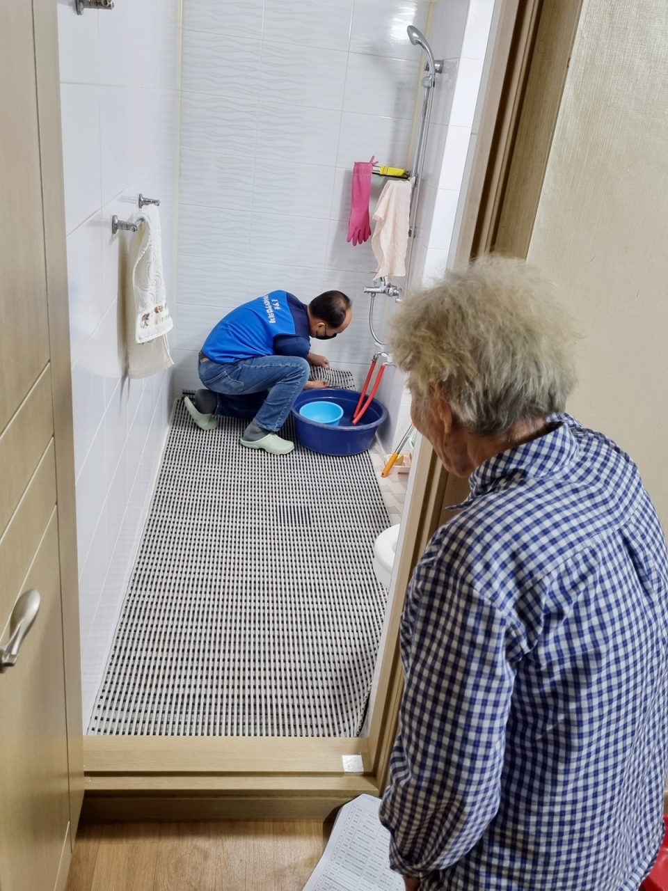 충주시 봉방동지역사회보장협의체가 지역 어르신가구에 욕실 미끄럼방지 매트를 설치하고 있다.