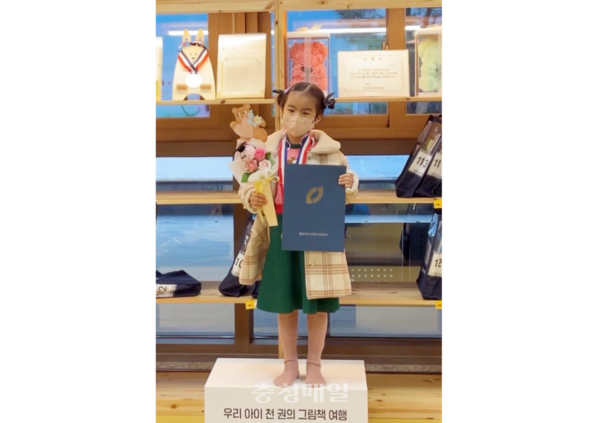 충북 청주오창소수도서관으로부터 천 책 읽기 달성 인증서와 금메달을 받은 김서아 어린이가 포즈를 취하고 있다.