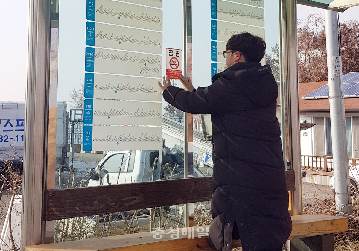 충북 청주 청원보건소 관계자가 버스정류소 금연구역 안내 스티커를 정비하고 있다.